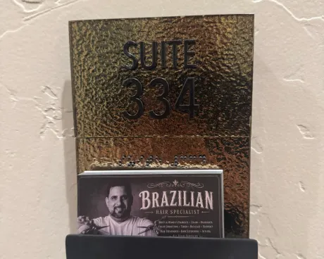 The door of suite 334, with his Brazilian hair specialist card beside it