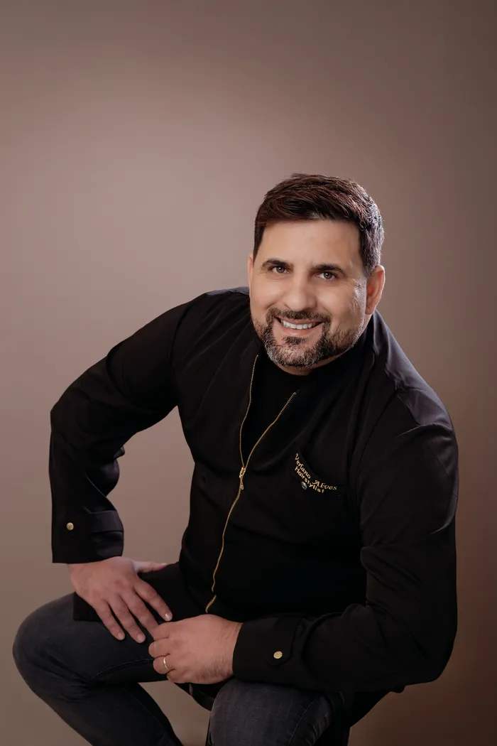 Verlano Alves smiling, wearing his black studio jacket with gold embroidery