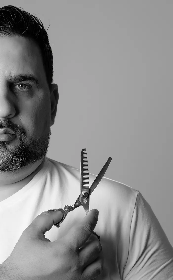Close portrait of Verlano Alves in black and white, holding thinning shears