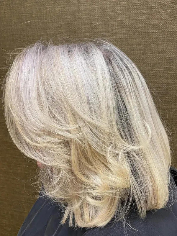 Pearl blonde cut in long feathered layers, seen from the side