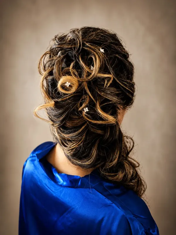 Curled updo pinned high and finished with a gold pin